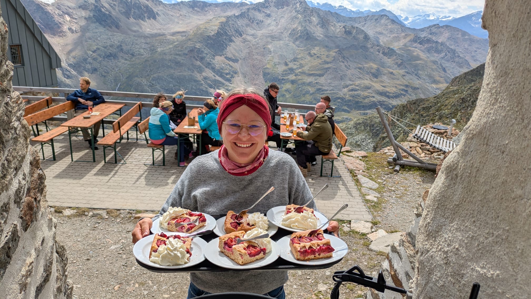 Zwetschgenkuchen mit Sahne, von einer herzlichen, strahlenden, Bedienung serviert auf der Sonnenbeschienen Terrasse